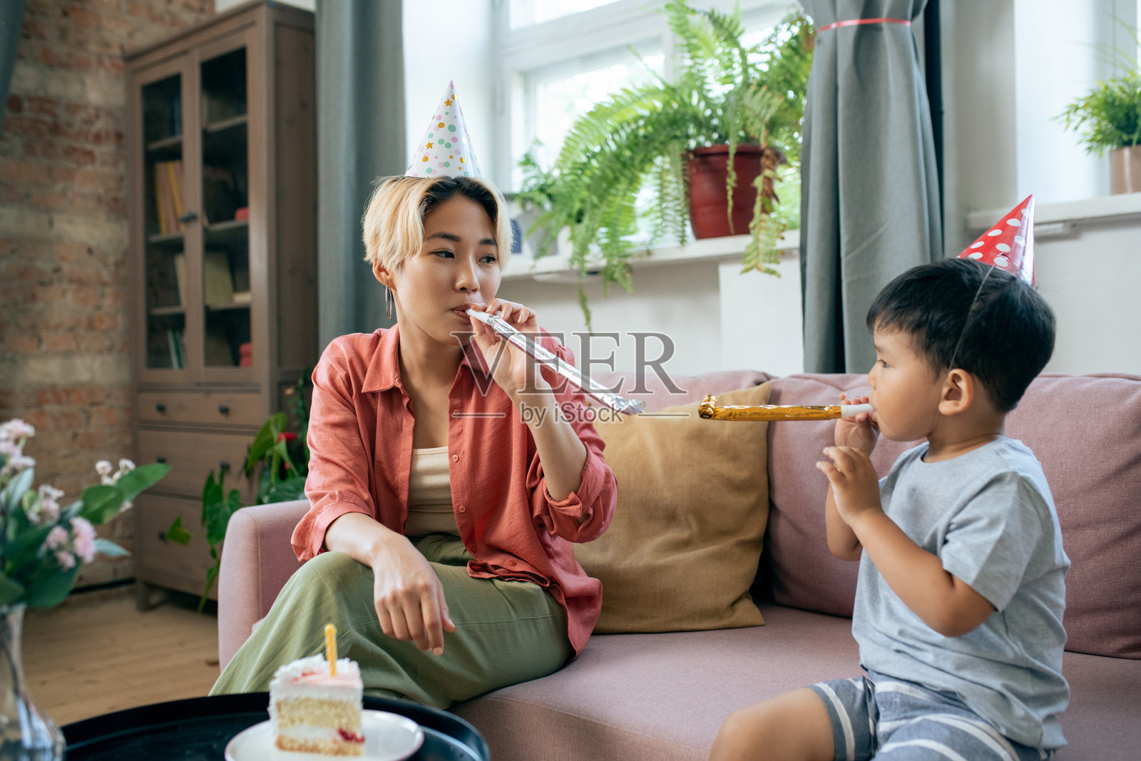妈妈和儿子在家里的生日聚会上吹口哨照片摄影图片
