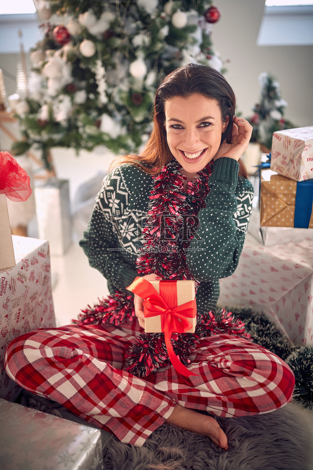 在一个美丽的节日早晨，在家里拿着圣诞礼物的女孩。照片摄影图片