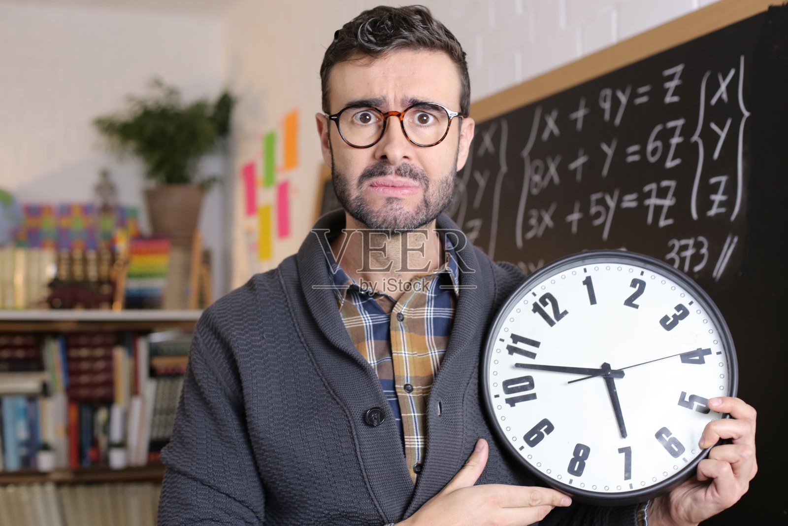 在教室里拿着钟的男人照片摄影图片