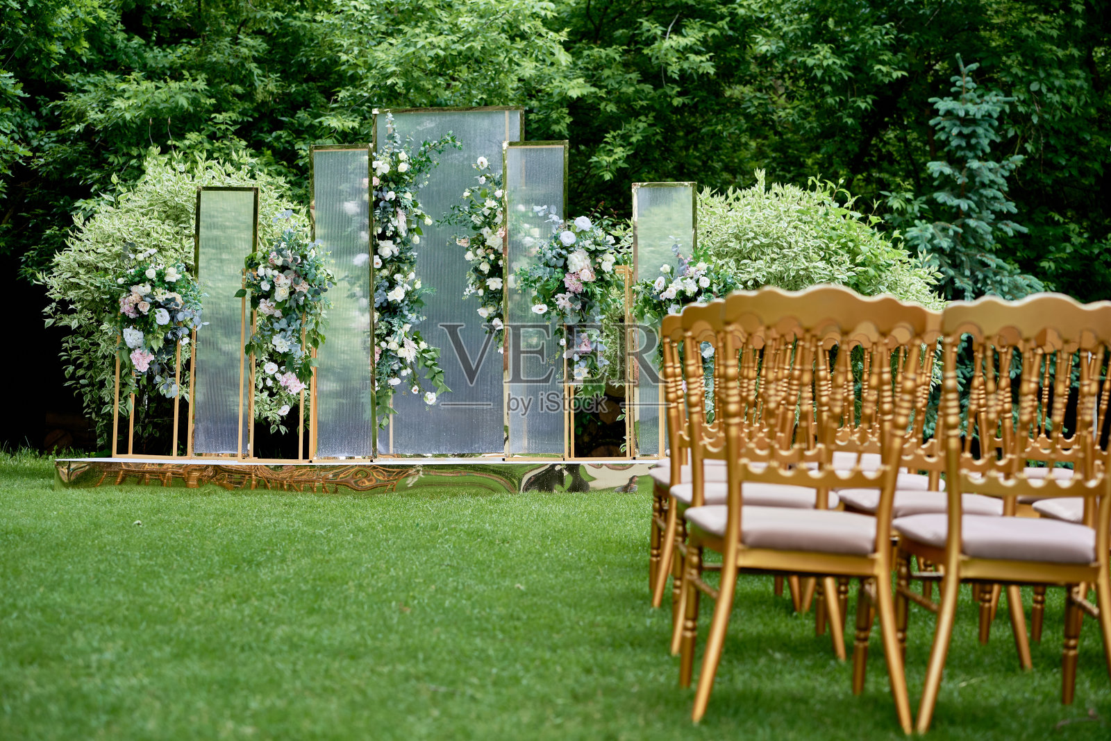 婚礼地点在室外花园，复制空间。婚礼拱门两侧装饰有鲜花和椅子。婚礼背景照片摄影图片