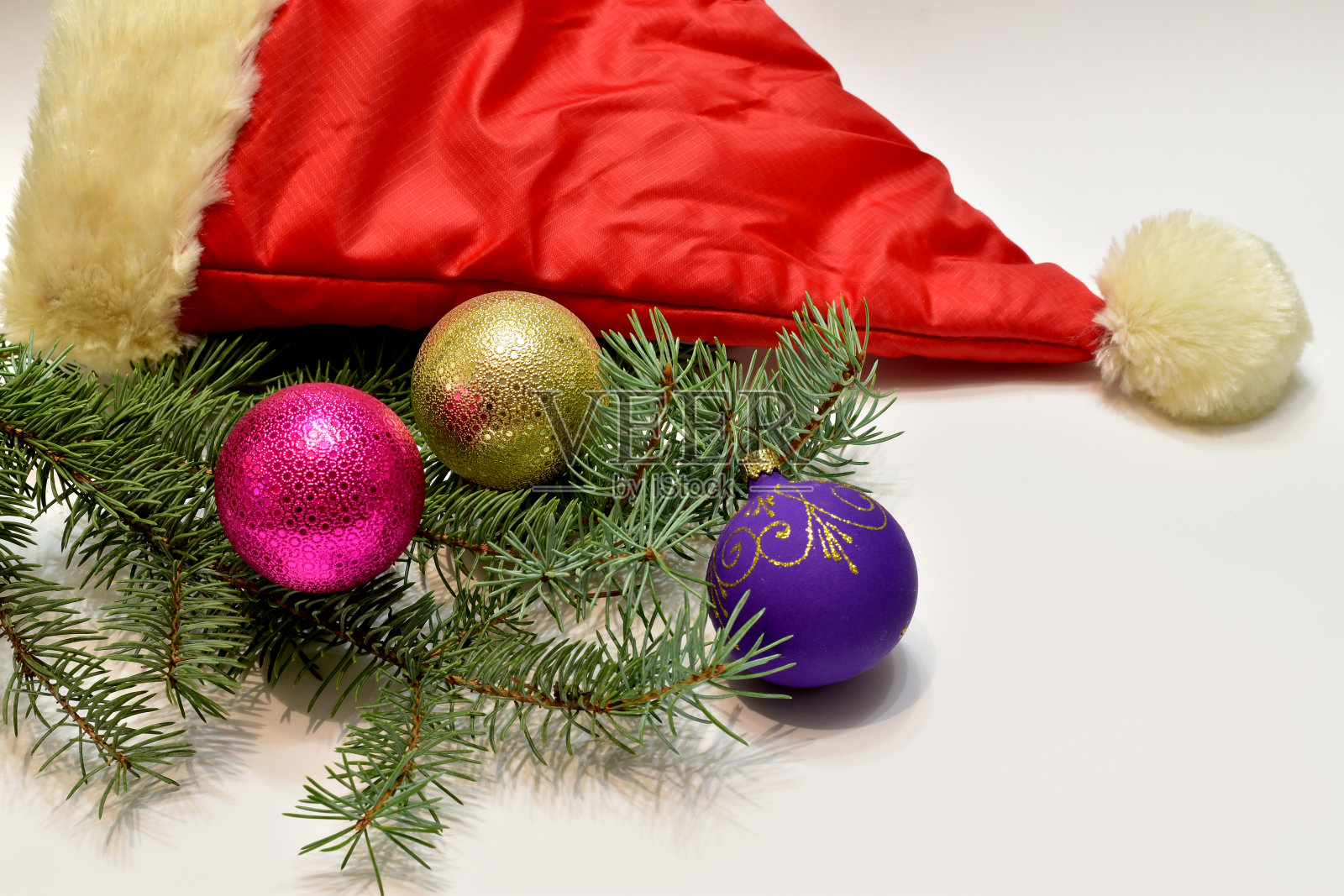 白色的桌子上放着三个玻璃球和一顶圣诞老人帽。照片摄影图片