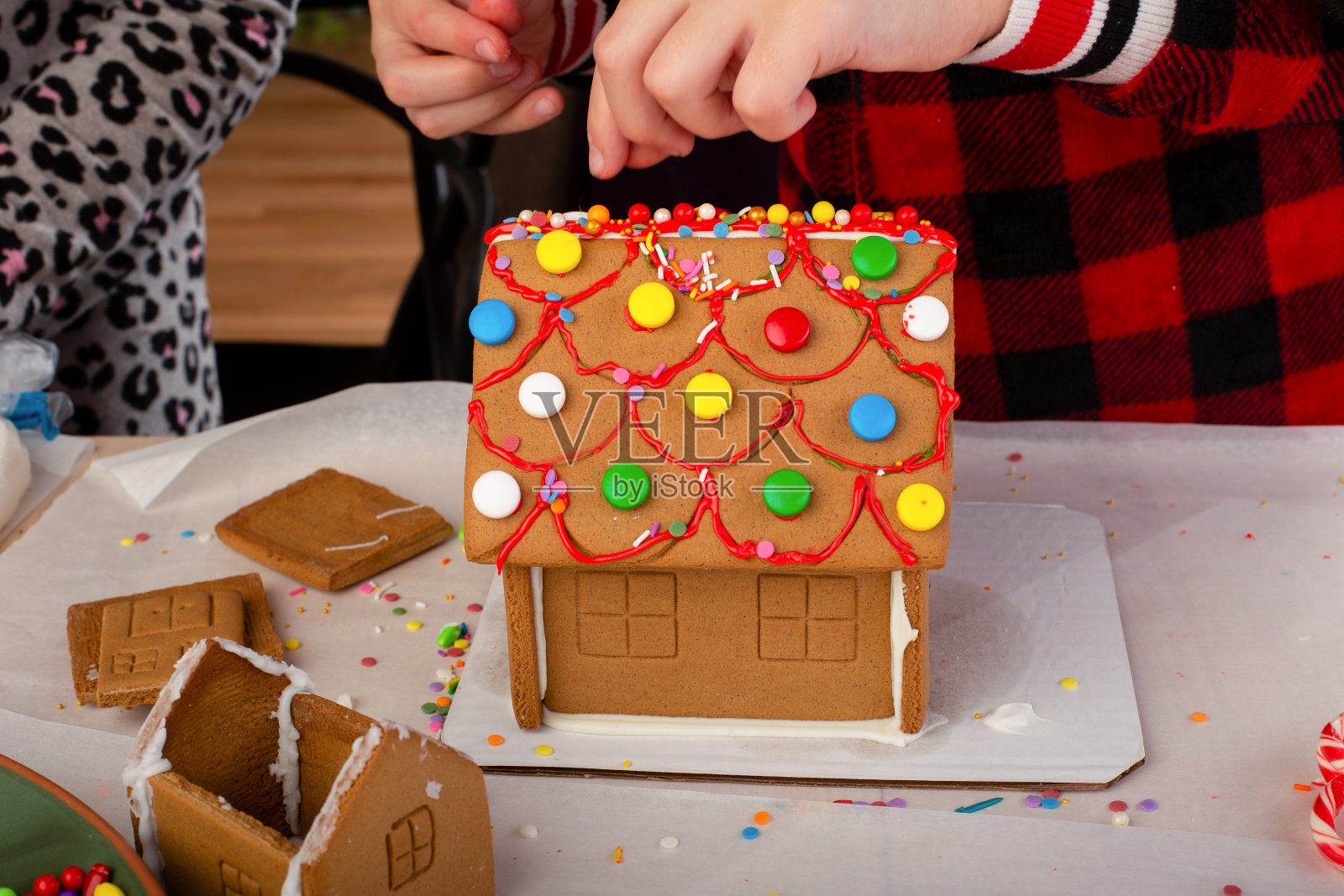 孩子们在圣诞节的时候组装和装饰一个姜饼屋。圣诞家庭传统，圣诞工艺品。照片摄影图片