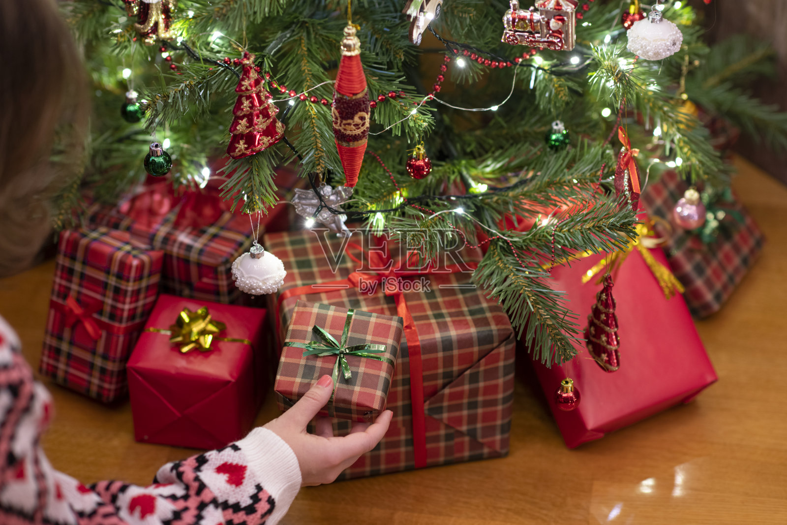 女人把礼品盒放在圣诞树下。提出了家庭。照片摄影图片