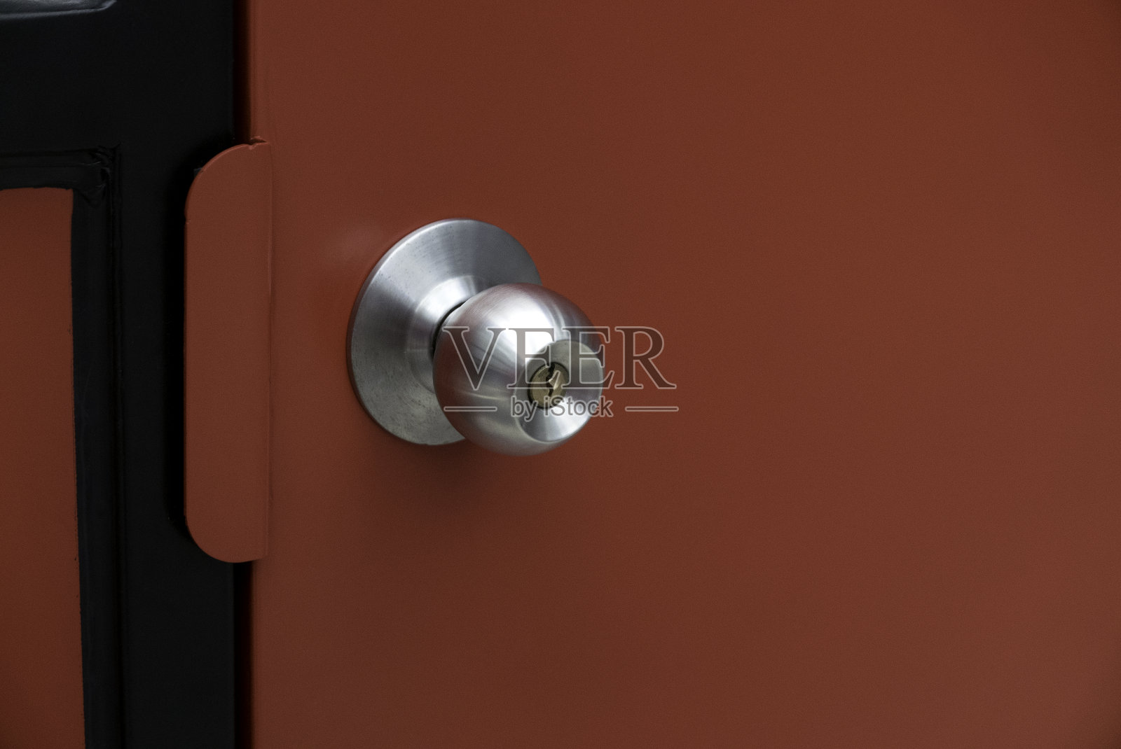 红色钢制门，配有不锈钢门把手。照片摄影图片