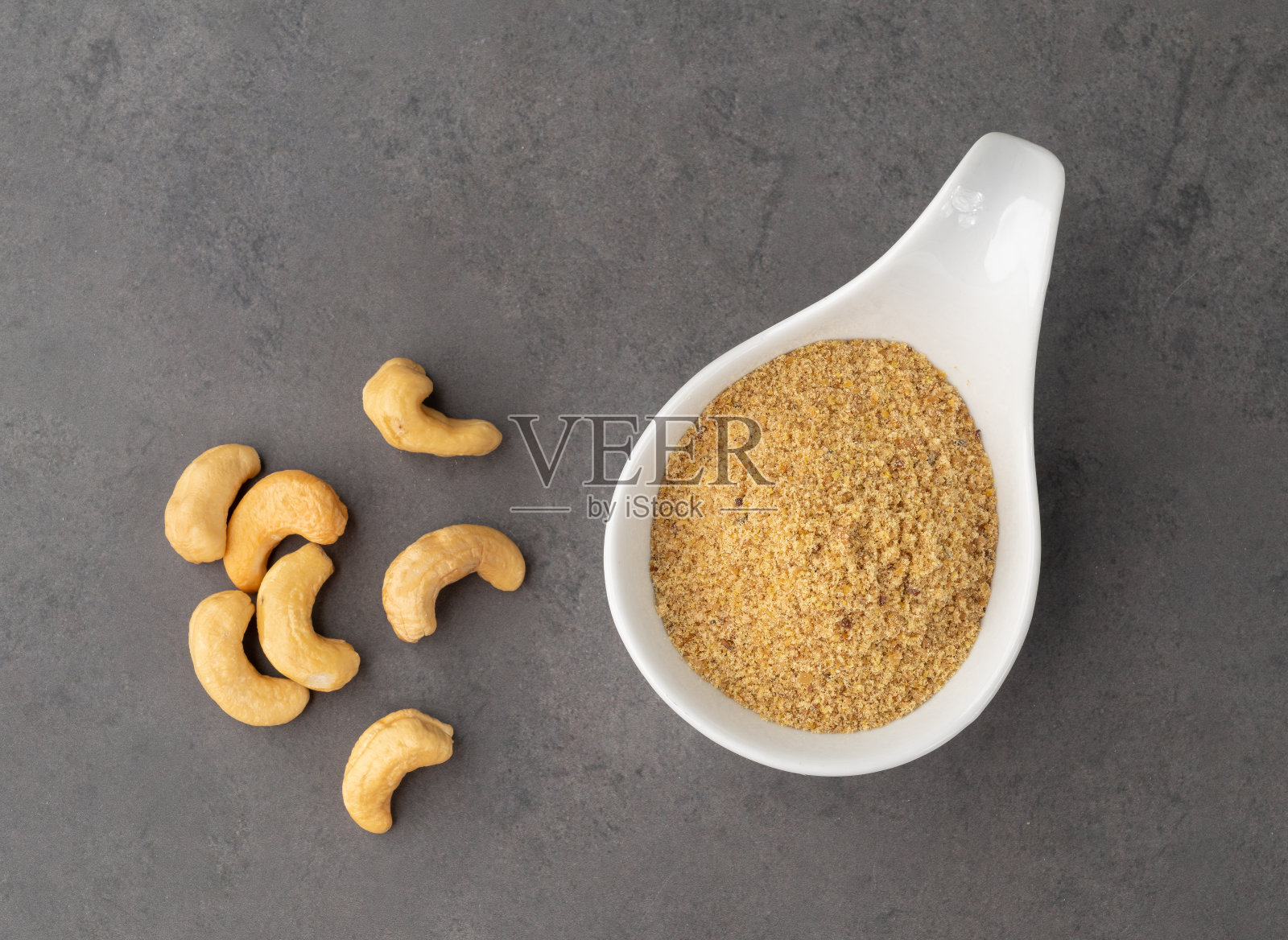 将腰果面粉放入碗中，置于石头背景上。无筋面粉照片摄影图片