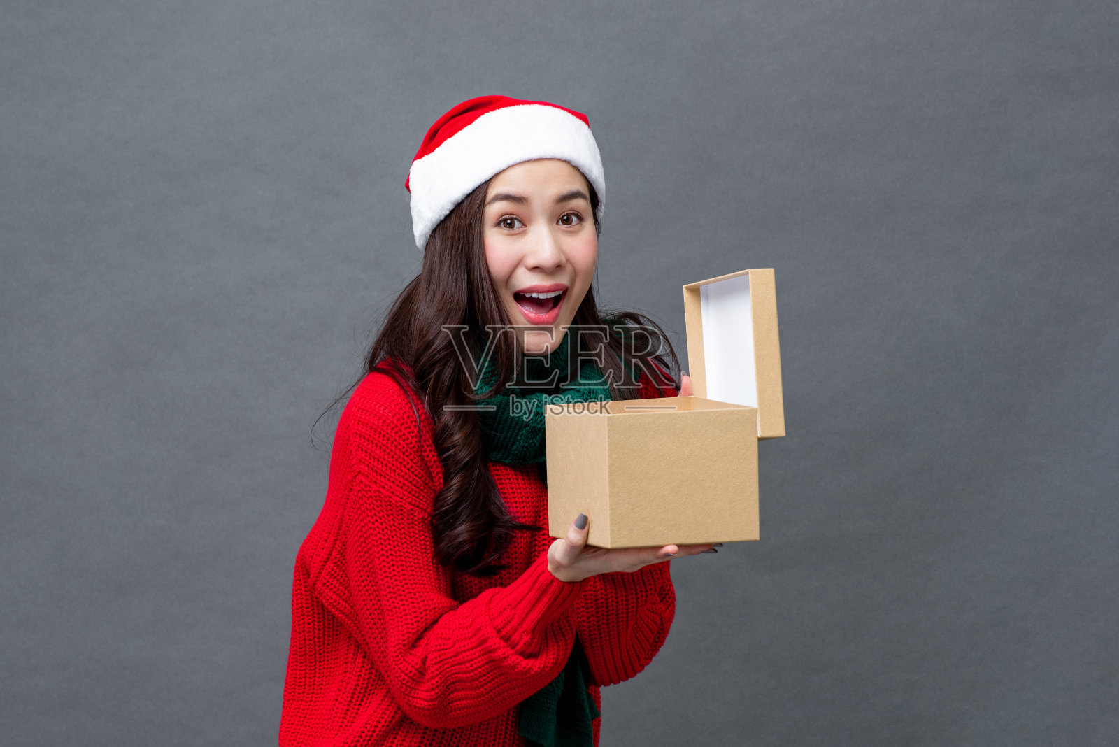 惊讶的年轻亚洲女人打开圣诞礼物盒在浅灰色工作室孤立的背景照片摄影图片