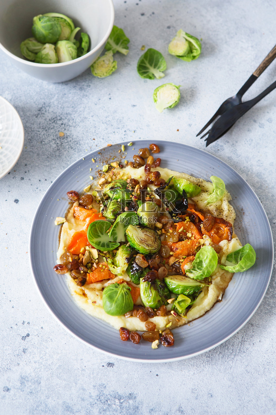 球芽甘蓝配开心果、葡萄干和马铃薯泥。健康的食物准备。植物性菜肴。绿色生活。素食食谱。食物的样式。素食菜。健康饮食照片摄影图片