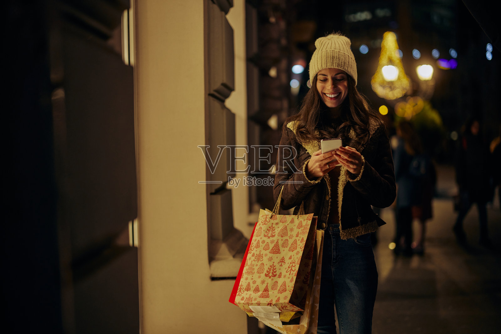 一个女人在圣诞节购物时，用手机，看着商店的橱窗照片摄影图片