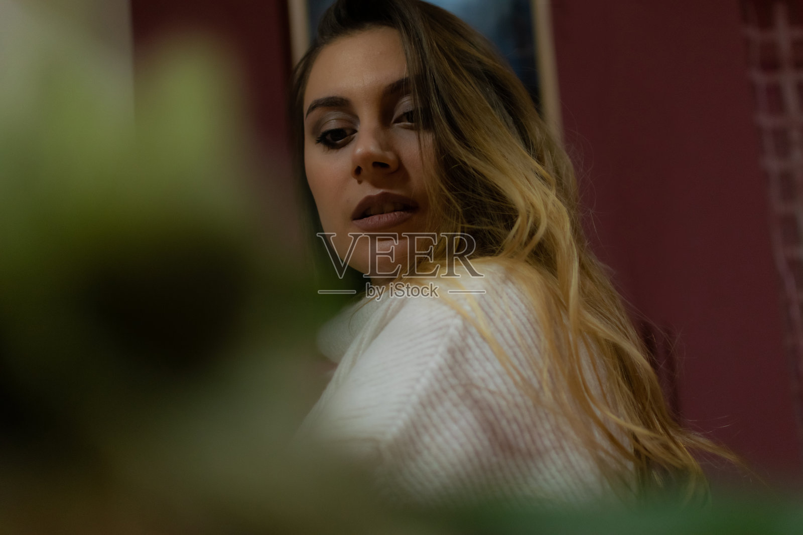 美丽的年轻女子享受她的周末和休息日，放松和享受在她的家，坐在客厅的沙发上，使用她的智能手机，与她的家人和朋友聊天和发短信。照片摄影图片