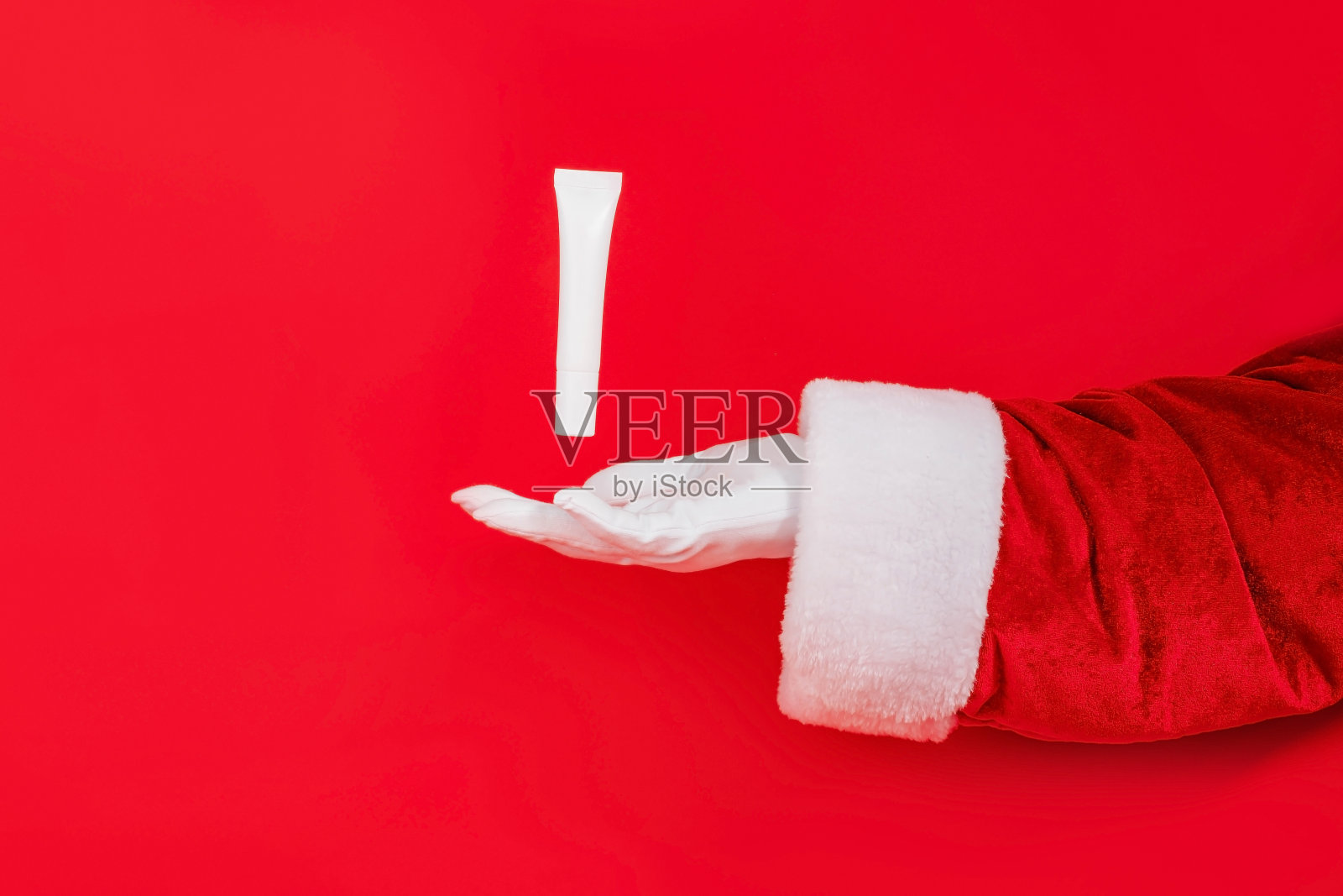 涂着化妆品的白色模型试管从圣诞老人的手上飞过。魔法，健康，假期的概念。照片摄影图片