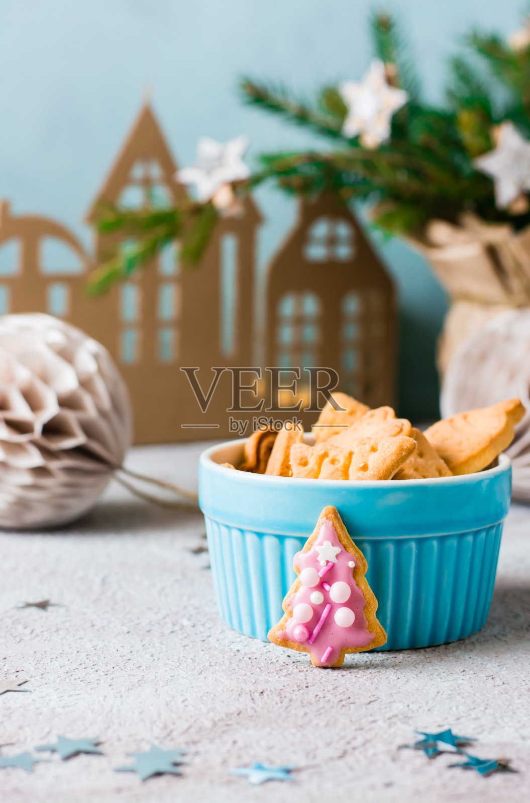 带粉色糖衣的云杉圣诞饼干被放置在装饰好的桌子上的一碗饼干旁边。节日的治疗。俯视图照片摄影图片