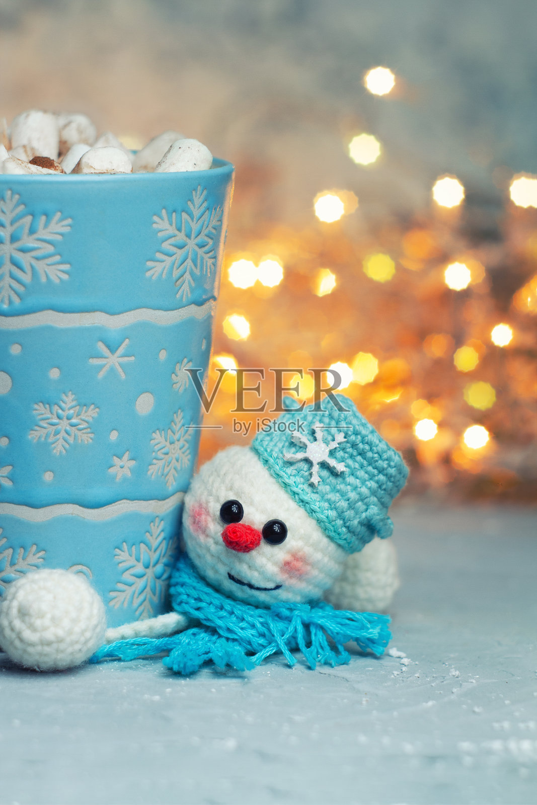 冬天的杯子与棉花糖和编织手工站雪人在围巾的背景下，节日的灯光散景照片摄影图片