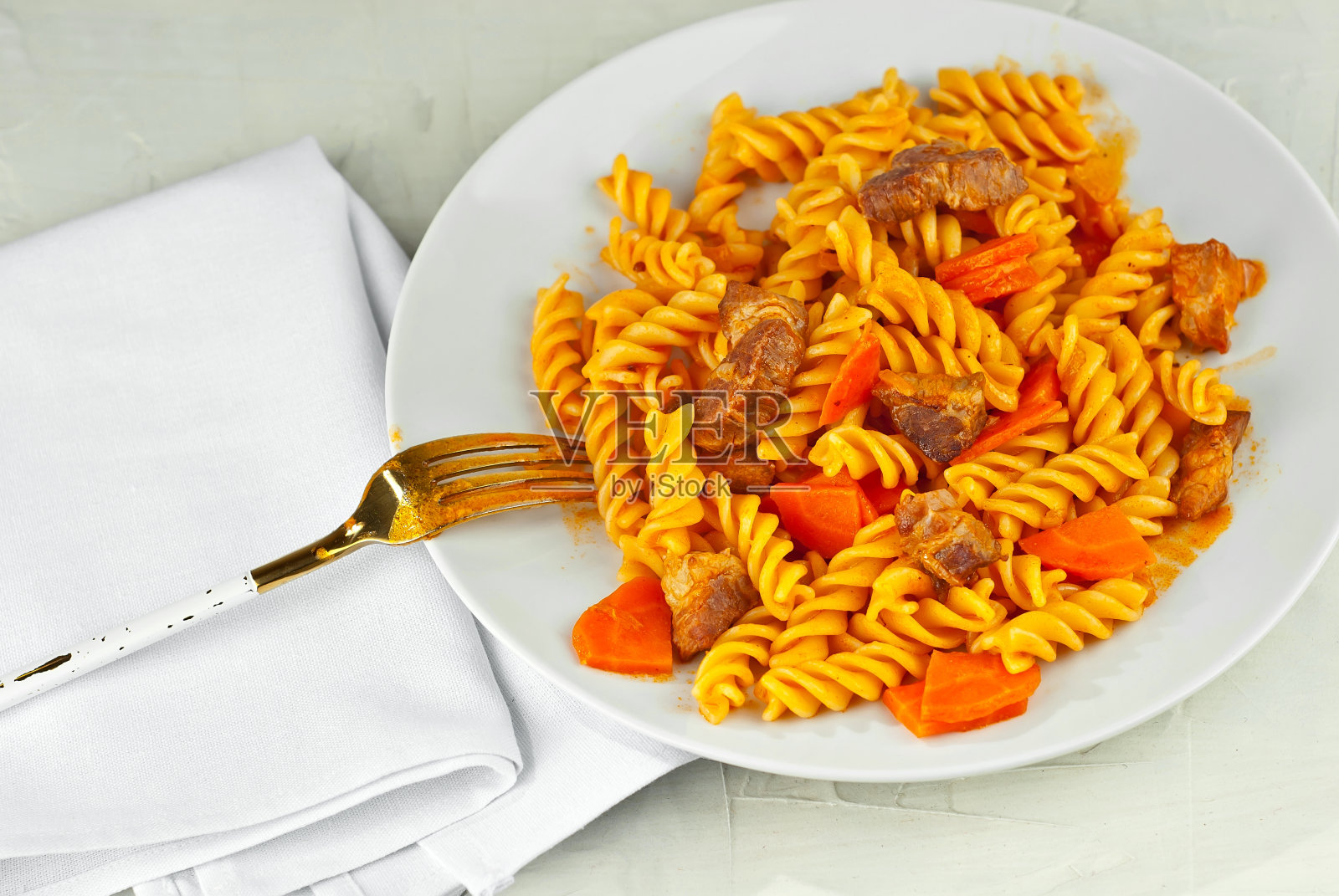 用白色盘子盛肉的意大利面。旧石桌上放着意大利面。照片摄影图片