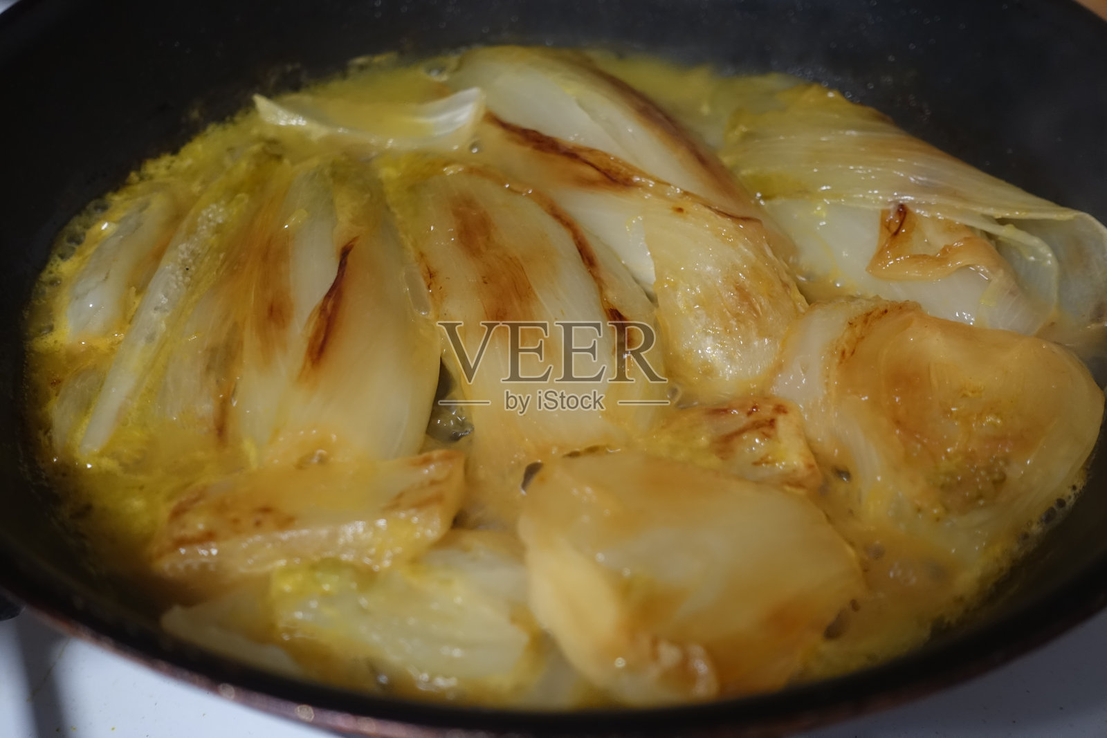 把茴香和菊苣放在平底锅里，在橙汁里煮法式烹饪法照片摄影图片