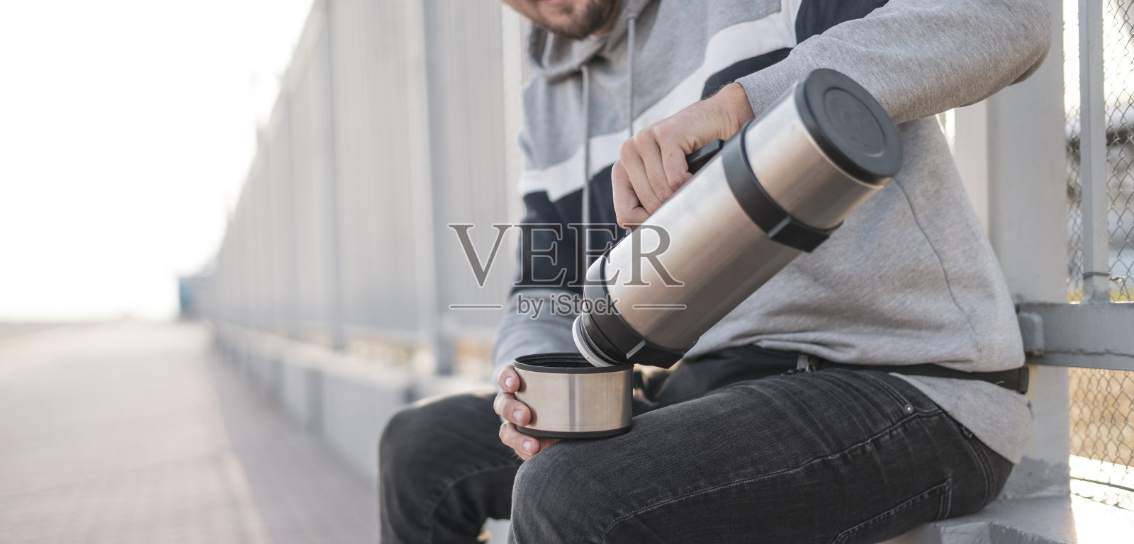 年轻男性手拿暖水瓶，倒热饮照片摄影图片