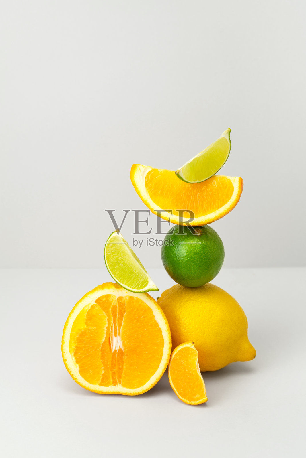 新鲜多汁橙半，柠檬，酸橙，橘子片平衡在灰色背景。早上可以用柑橘类水果做果汁或奶昔。健康饮食营养与维生素c，时髦的柠檬水成分照片摄影图片