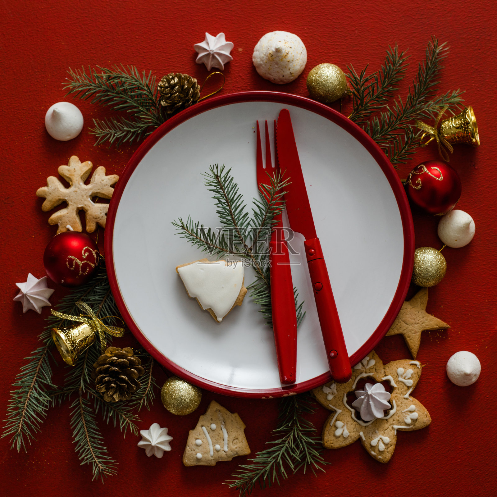 圣诞和新年摆桌。白色的空盘子上有餐具和圣诞树的树枝，红色的餐巾在红色的混凝土背景上。照片摄影图片