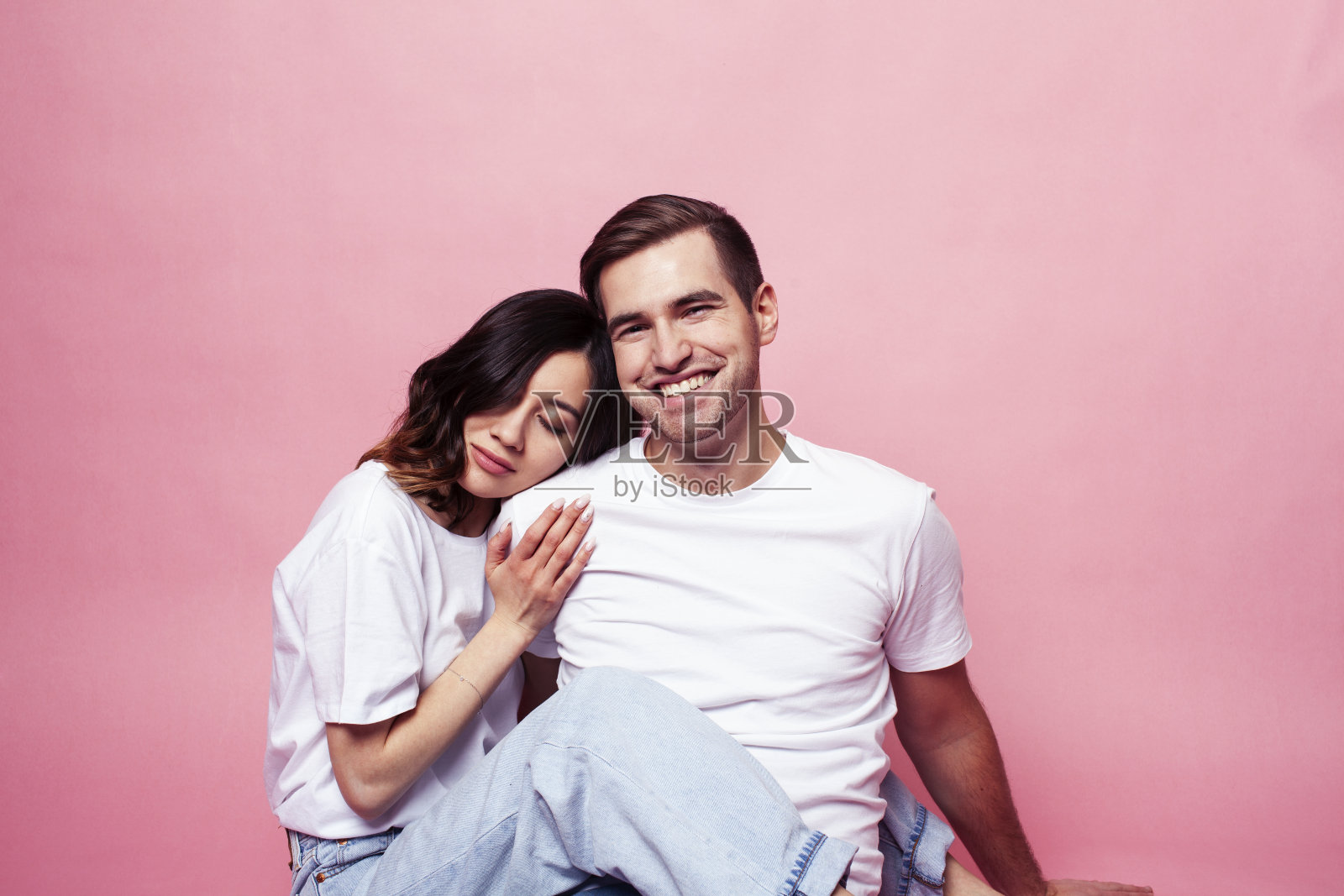 年轻开朗的白人夫妇在一起玩在粉红色的背景，男孩和女孩现代关系，生活方式的人的概念照片摄影图片