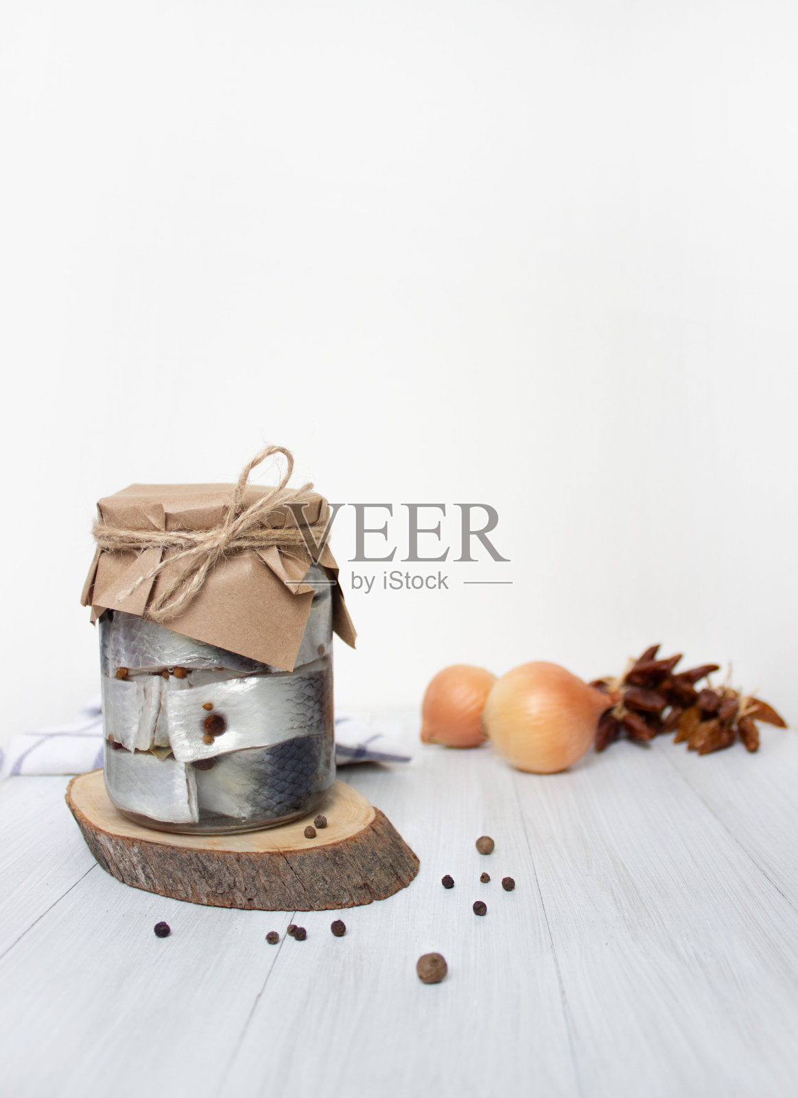 腌鲱鱼、胡椒和香料放在桌子上的罐子里，浅色背景，垂直照片照片摄影图片