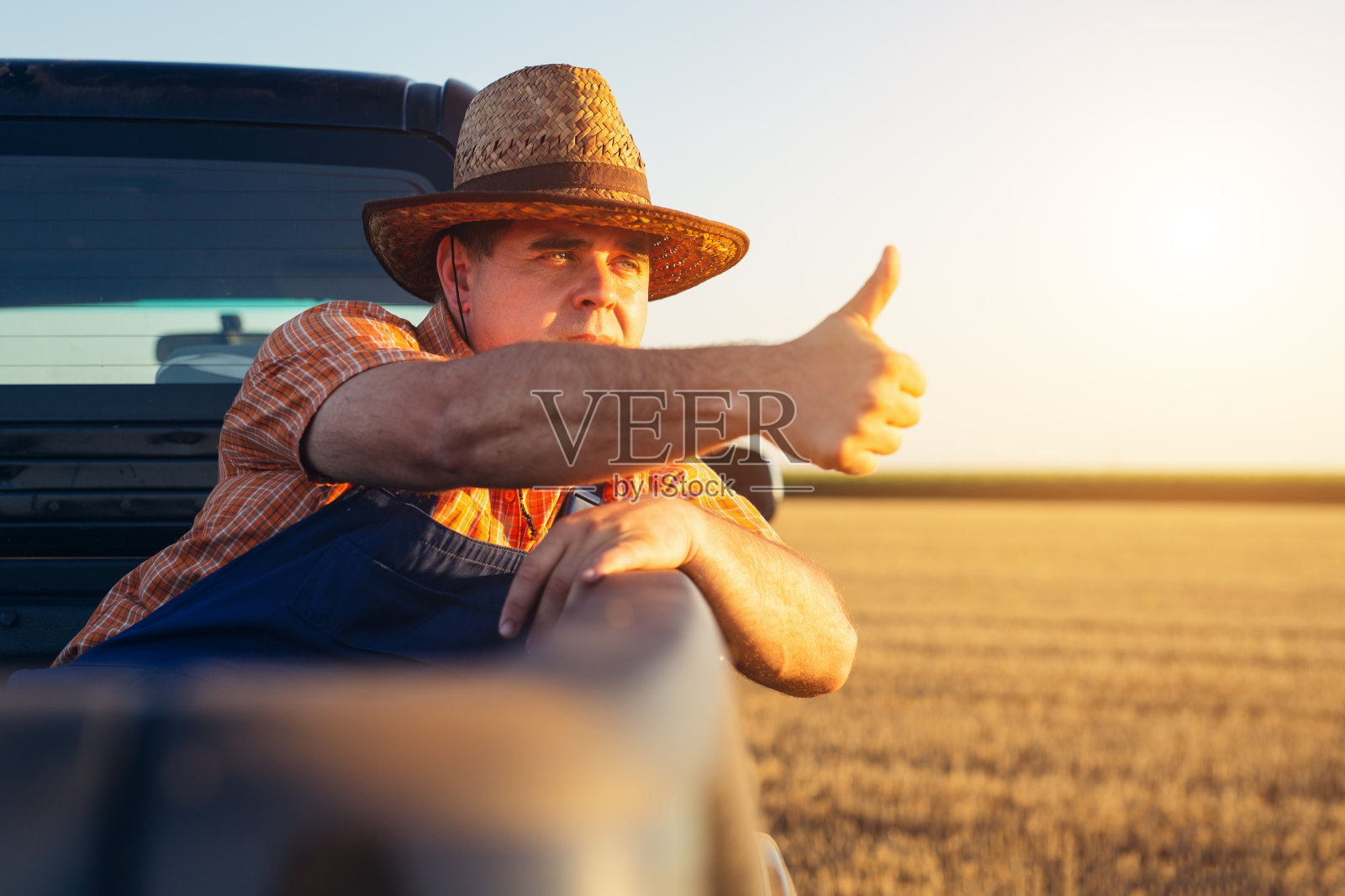 农夫坐在卡车后面。照片摄影图片