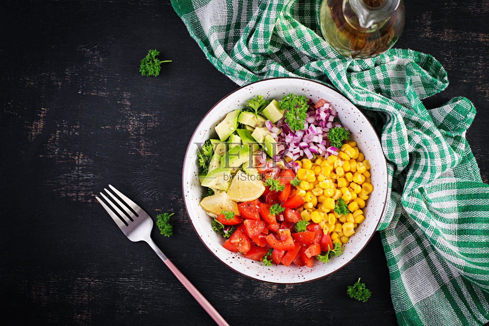 碗里有牛油果、西红柿、红洋葱和甜玉米的沙拉。素食者佛陀碗。素食食物。俯视图，平铺照片摄影图片