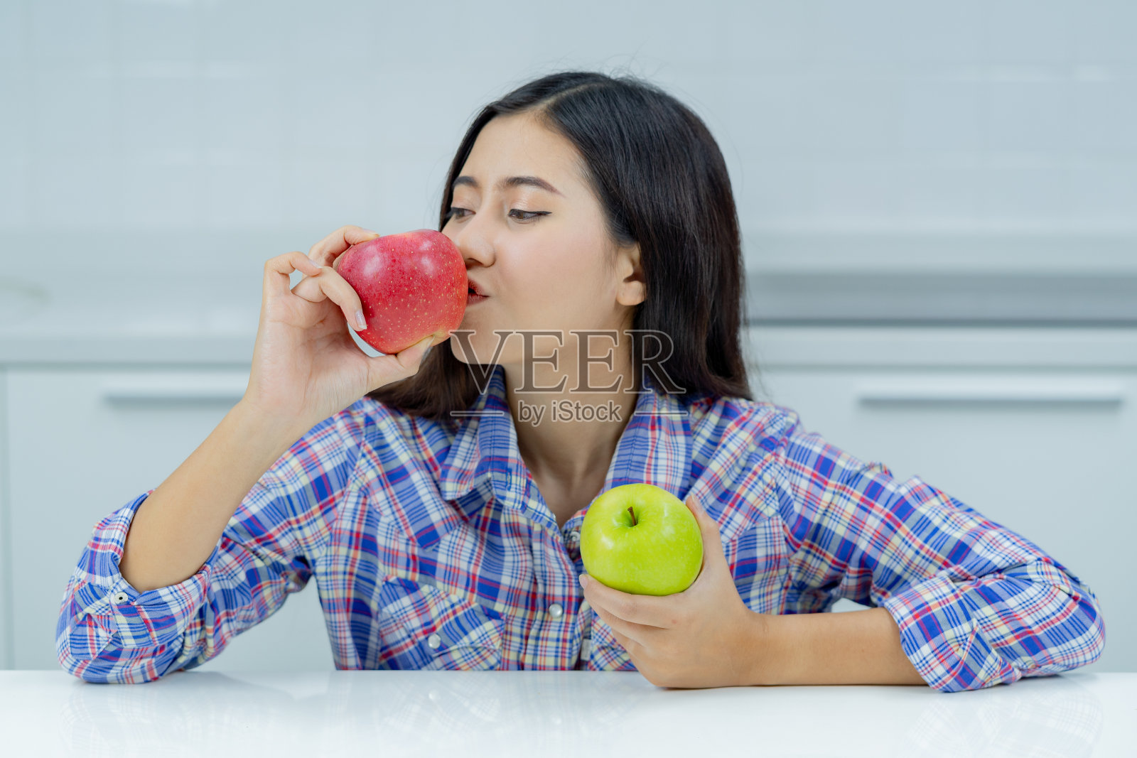 亚洲妇女高兴地拿着绿苹果和红苹果。照片摄影图片