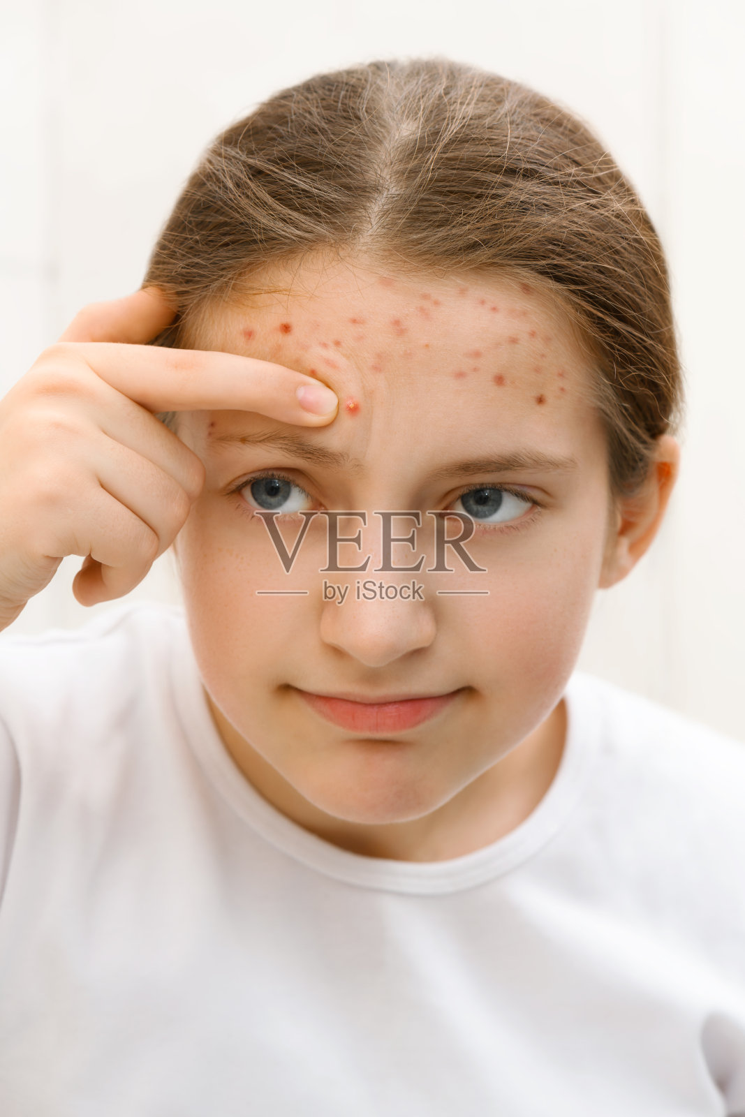 少女看着镜子，用手触摸脸庞，肌肤干净，美丽又健康照片摄影图片