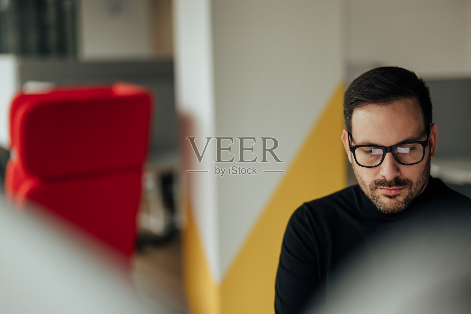 这是一张专注的成年员工，坐在他的小隔间里，忙着工作的照片。照片摄影图片