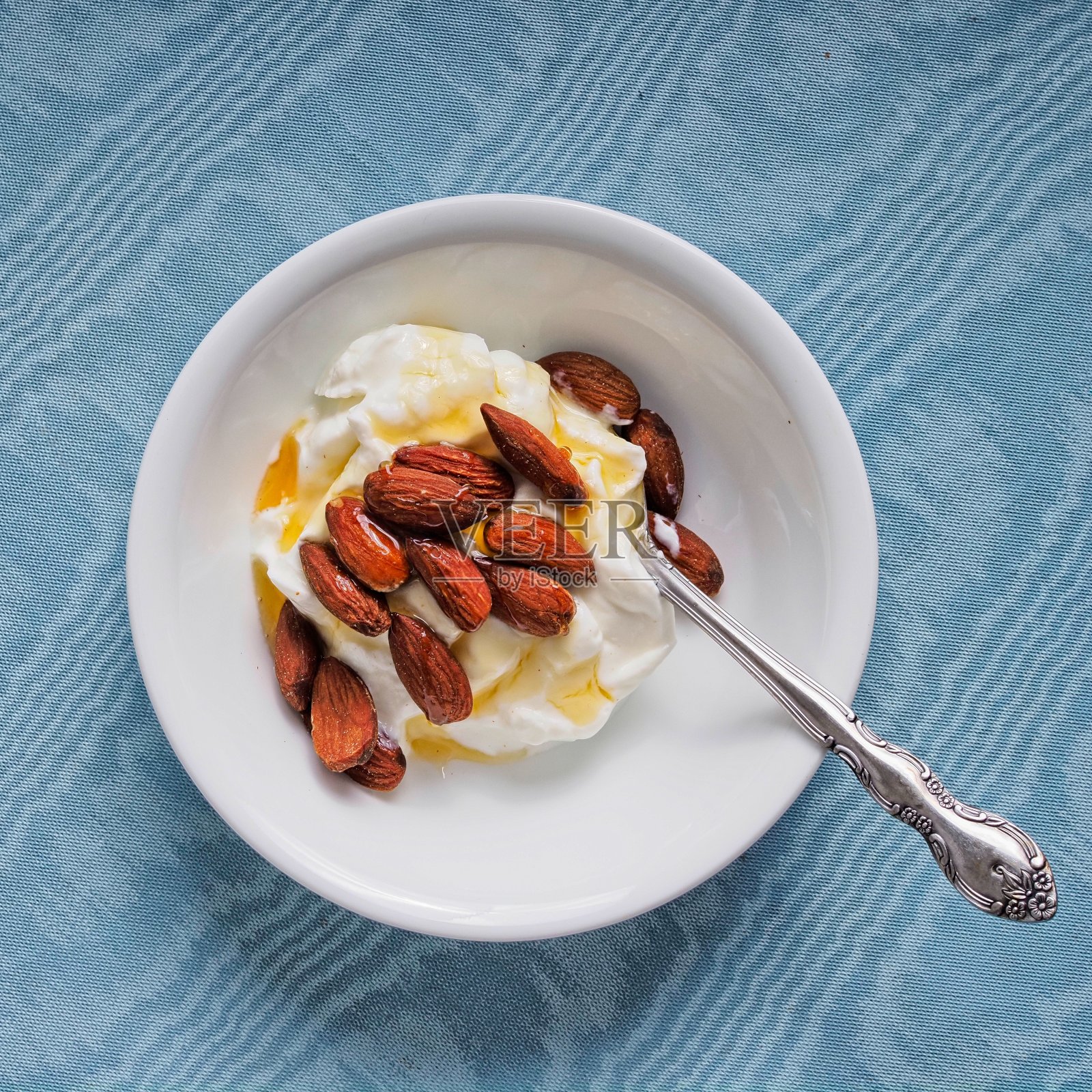 这是一种健康的零食，上面有新鲜的希腊酸奶和甜蜂蜜杏仁照片摄影图片