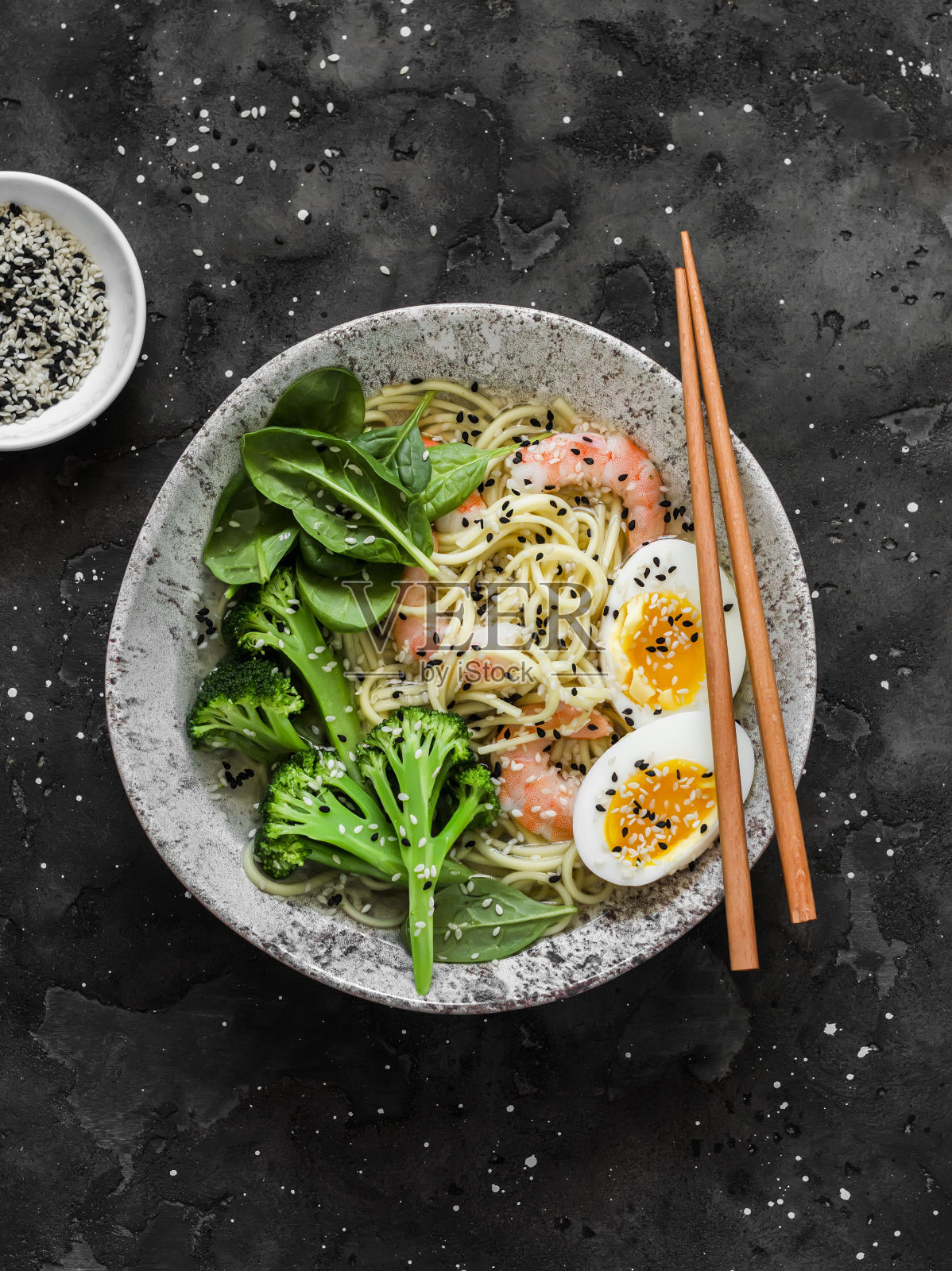 拉面有虾，西兰花，菠菜和煮鸡蛋，背景为黑色，俯视图。美味的亚洲风味午餐照片摄影图片