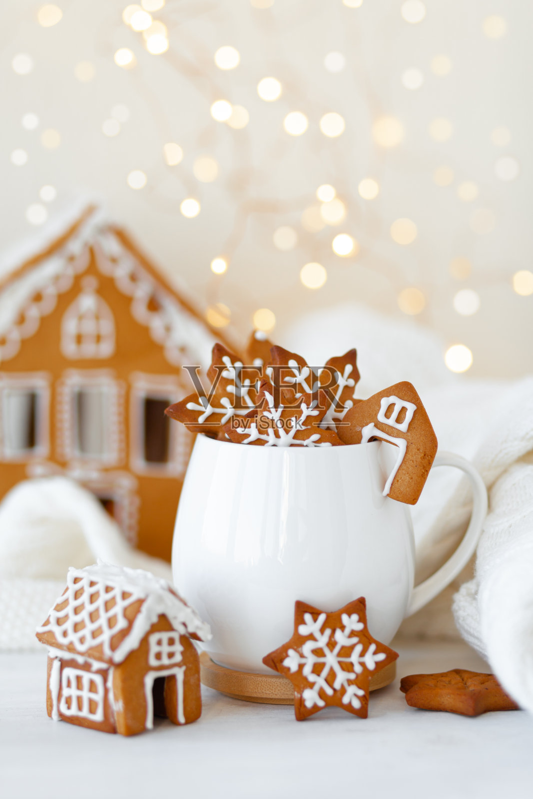 圣诞作文与白色杯子热巧克力和姜饼饼干。房子的背景。假日氛围，舒适的手工装饰。圣诞树小彩灯,散景。近距离照片摄影图片