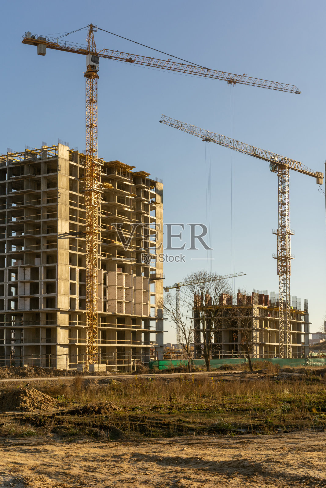 建筑工地的垂直照片，高楼大厦和起重机映衬着蓝天在城市里。建筑的概念照片摄影图片