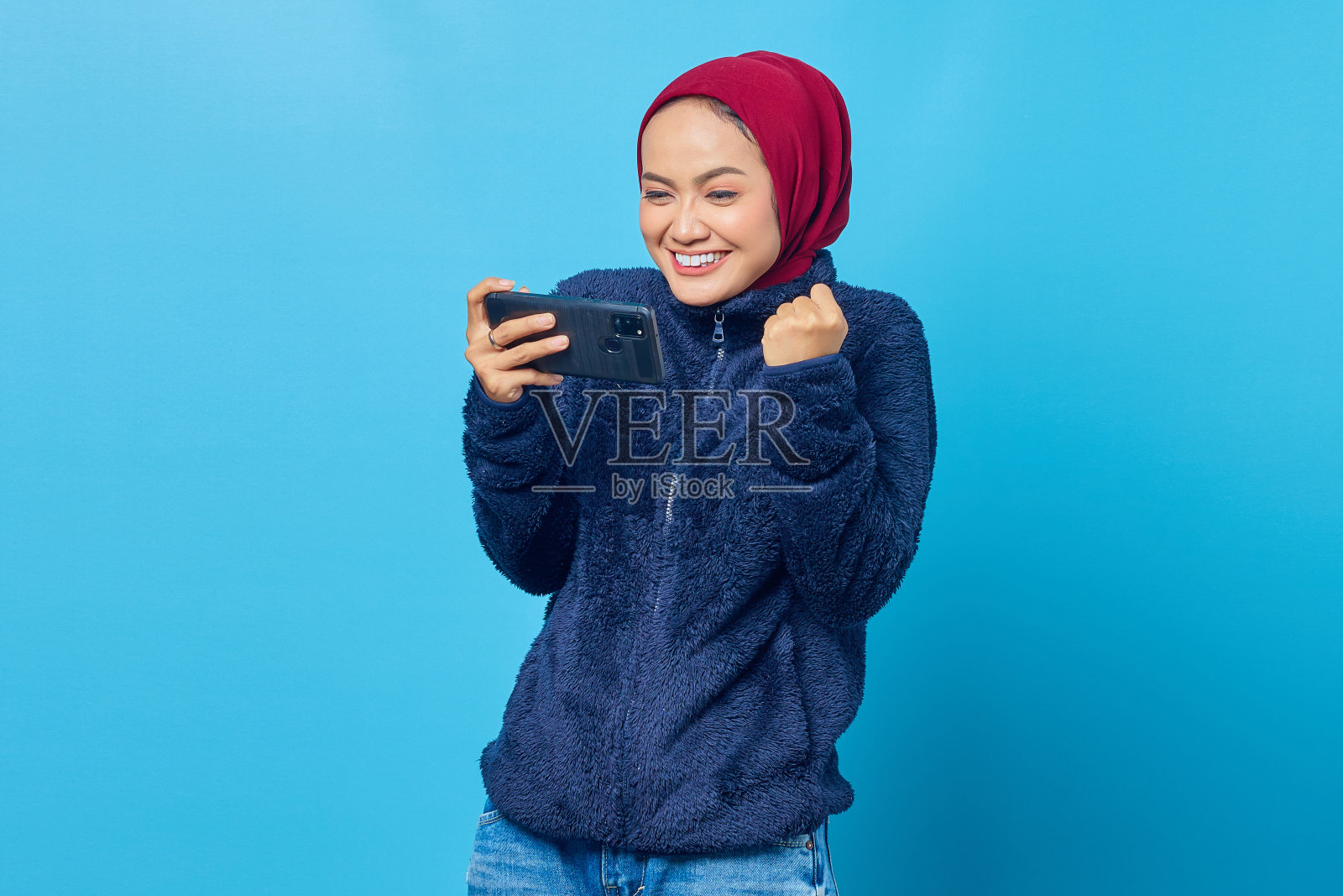 肖像的热情的亚洲妇女玩游戏的手机和庆祝胜利照片摄影图片