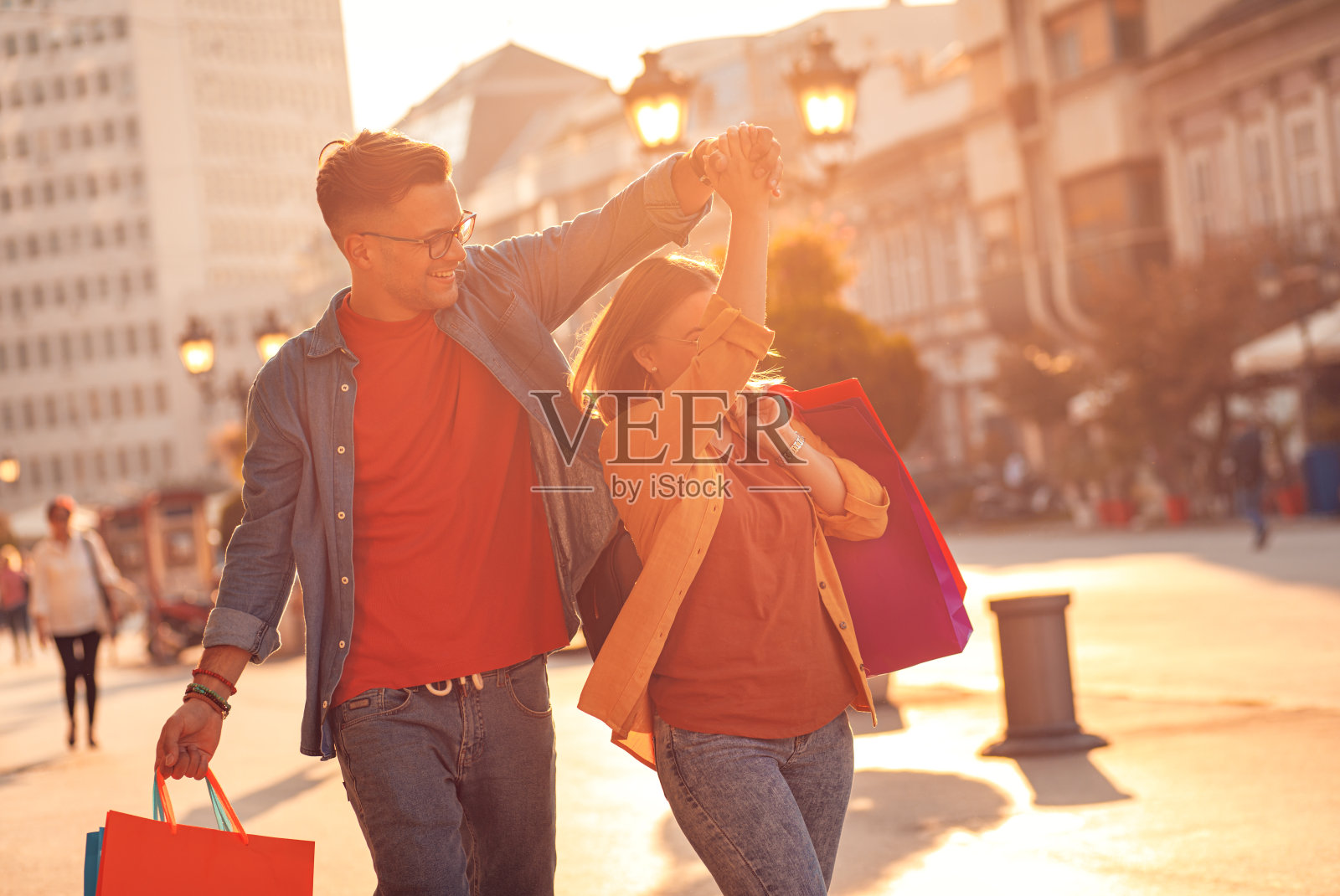 微笑的年轻夫妇走在城市街道一起享受购物。照片摄影图片