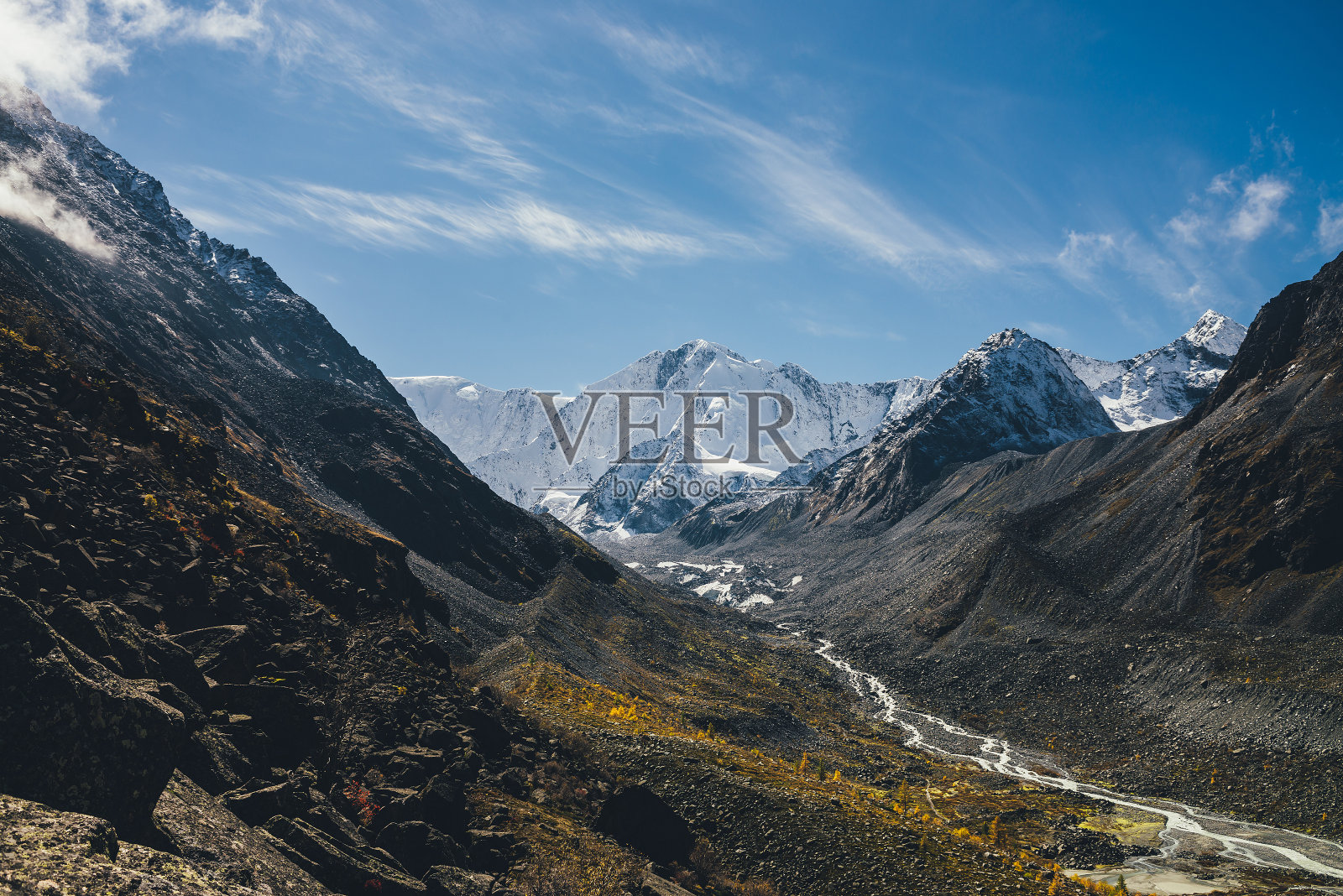 美丽的高山景观，有巨大的雪山和山河，在秋天的阳光下，溪流在岩石之间的山谷中。秋天阳光灿烂，高山雪山墙高耸照片摄影图片