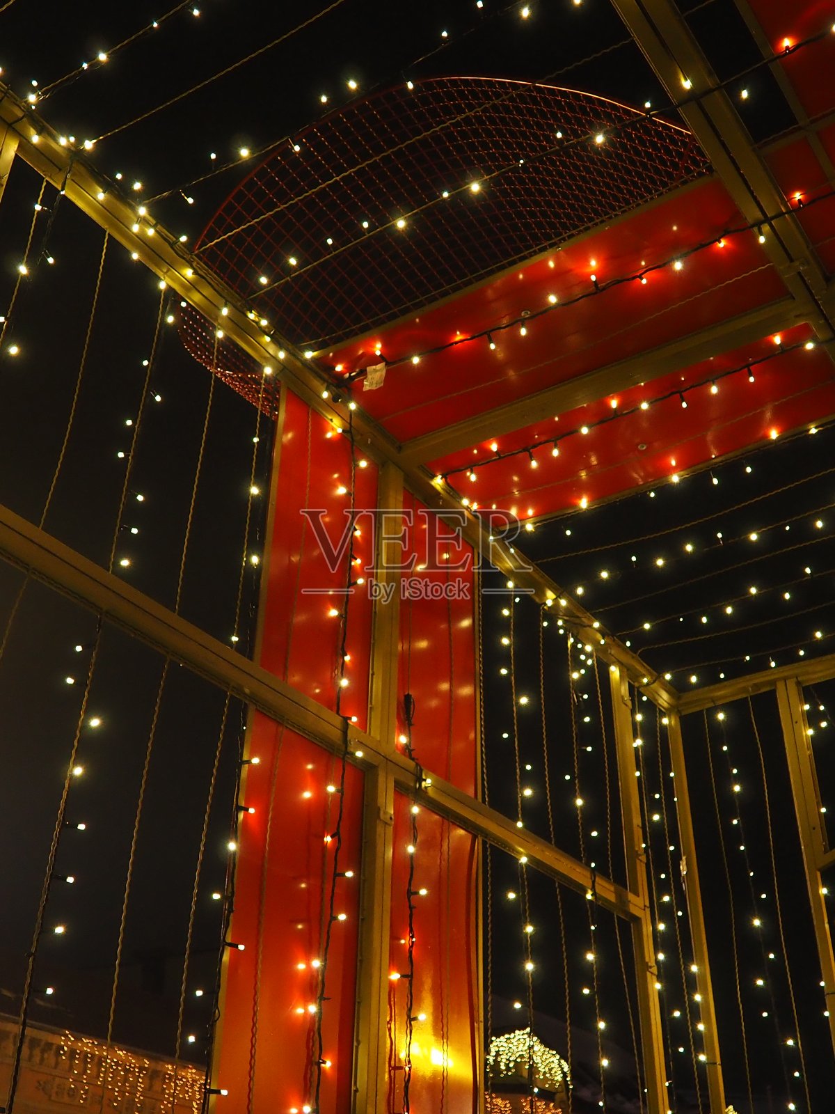 美丽的花环装饰着市中心。新年和圣诞的街道装饰。黑暗中闪烁着无数黄色和白色的灯泡。五彩装饰设计和散景。照片摄影图片