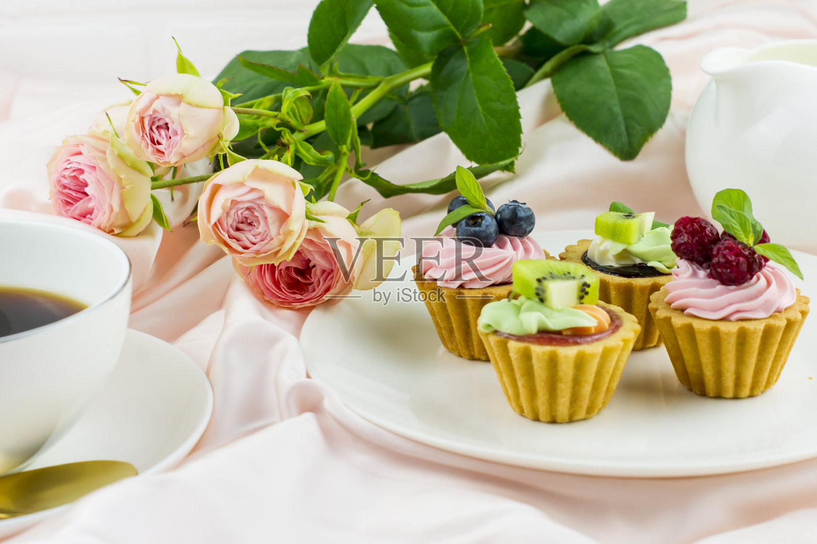 浪漫的构成为情人节，节日，生日。盘子里放着奶油和水果的迷你馅饼，一杯咖啡，一束玫瑰。照片摄影图片