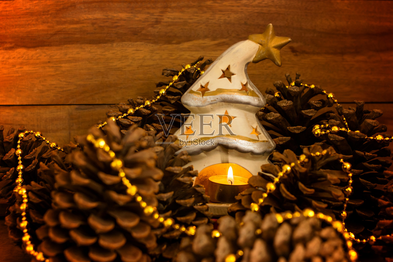 圣诞树形状的灯笼上有点燃的蜡烛和一套松果和金色的装饰物照片摄影图片