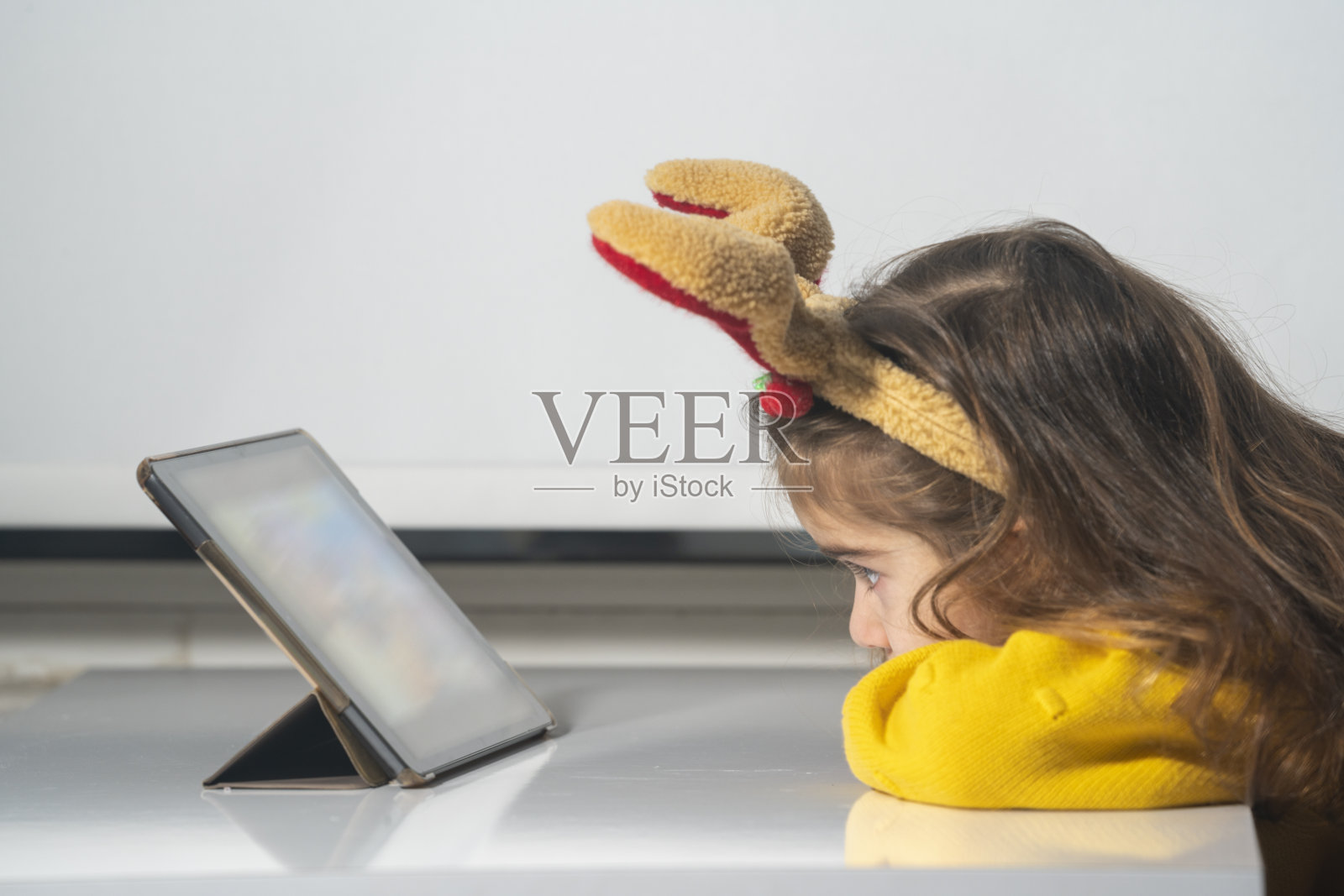 照片中的女孩穿着服装驯鹿鹿角使用数字平板电脑照片摄影图片