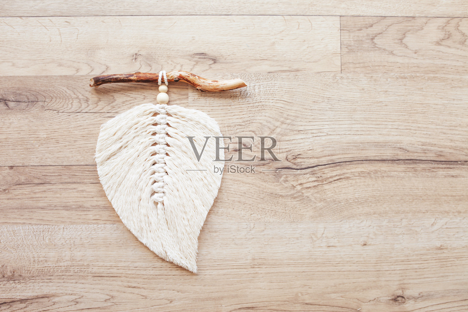 自然颜色的流苏叶和丝线缠绕躺在木制的桌子上。棉绳装饰流苏，让您的房间更舒适和独特。女人的爱好。手工挂墙装饰。本空间照片摄影图片