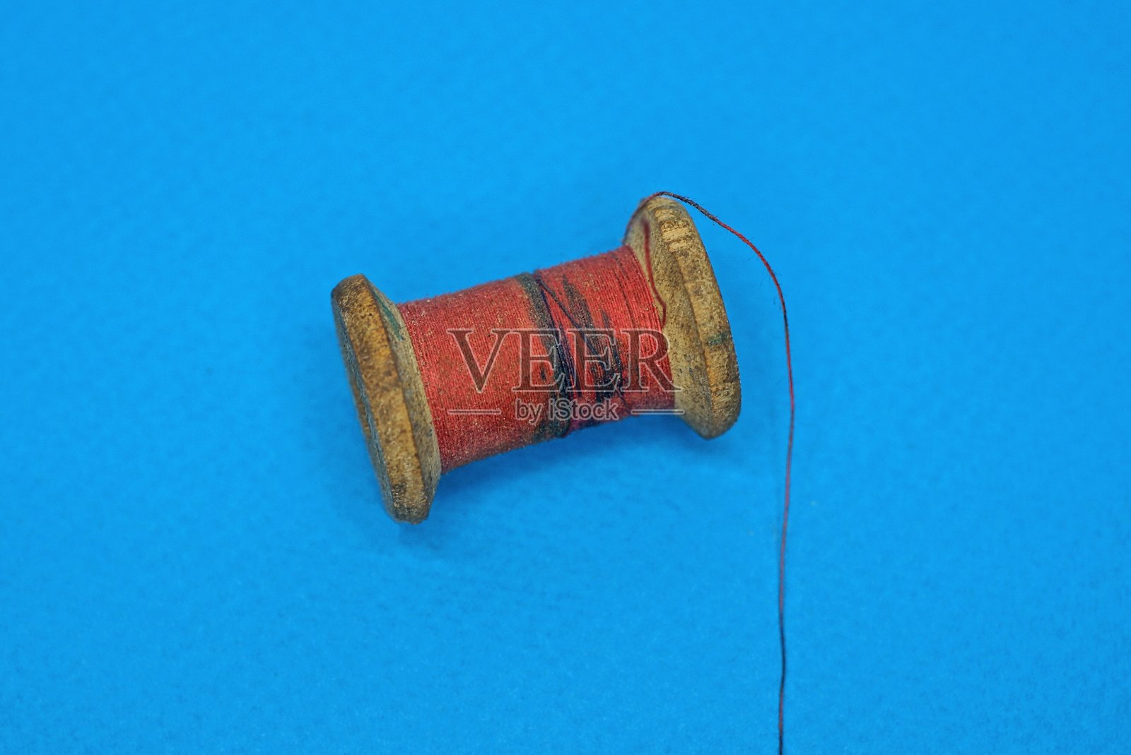 一个棕色的旧木线轴，上面有红色的脏线照片摄影图片