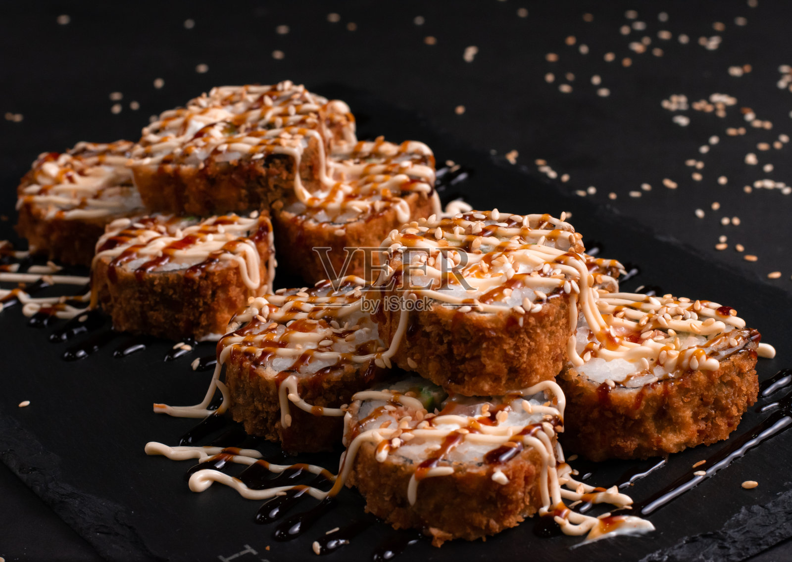 烟熏天妇罗寿司卷。美味的新鲜寿司卷与鲑鱼在黑色的背景。日本东方美食照片摄影图片