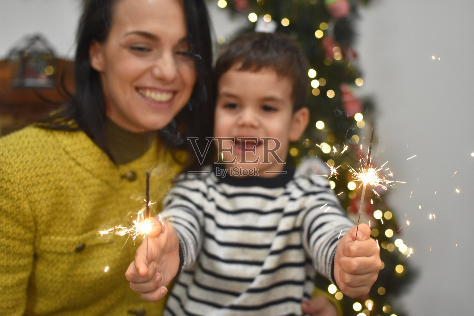 妈妈和儿子在圣诞树前玩烟火照片摄影图片