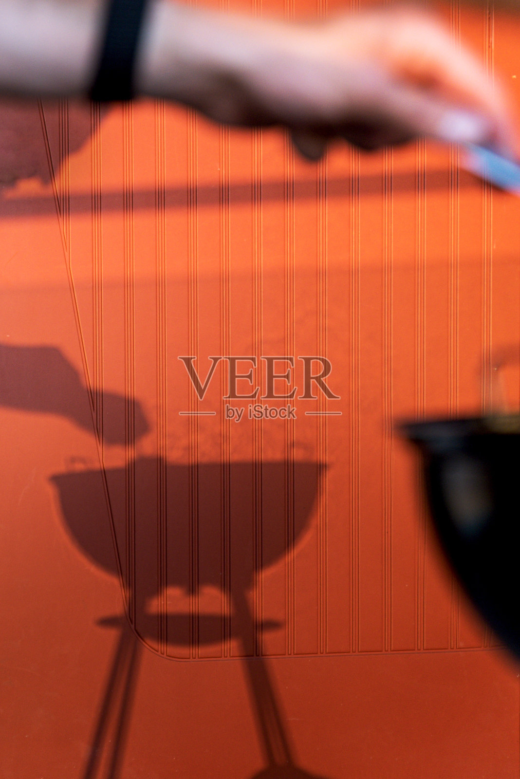 户外概念和烧烤:红色墙壁上的烟火阴影。一只模糊的手移动烤架上的烤肉或鱼。烟雾传达了夏天或炎热的季节照片摄影图片