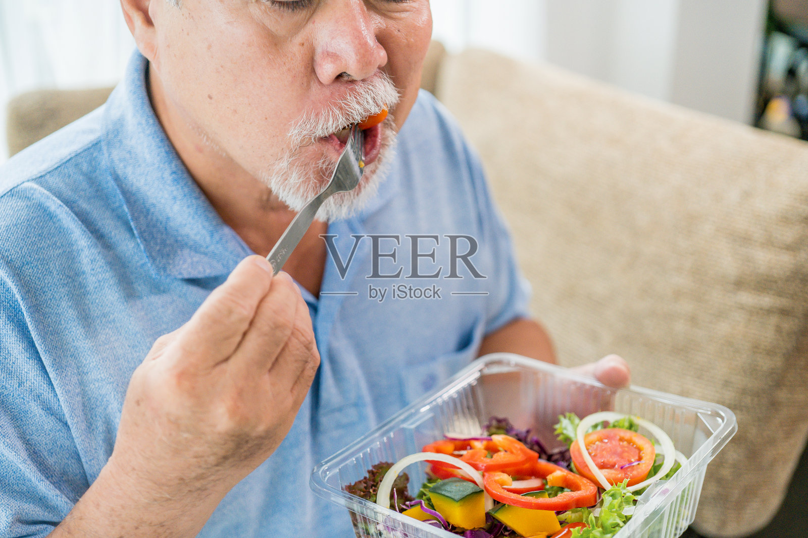 成熟的男人有健康的食物，肖像亚洲老人在家里吃沙拉，老年男性保健吃蔬菜和有用的食物。照片摄影图片