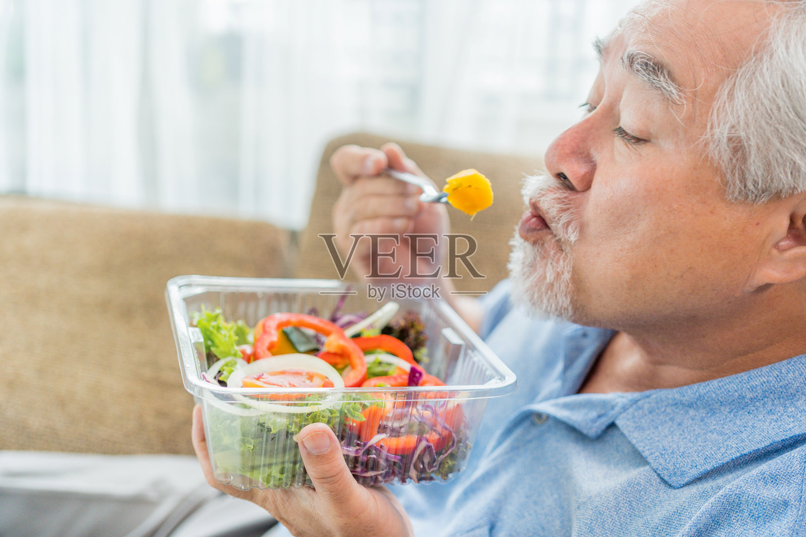 成熟的男人有健康的食物，肖像亚洲老人在家里吃沙拉，老年男性保健吃蔬菜和有用的食物。照片摄影图片