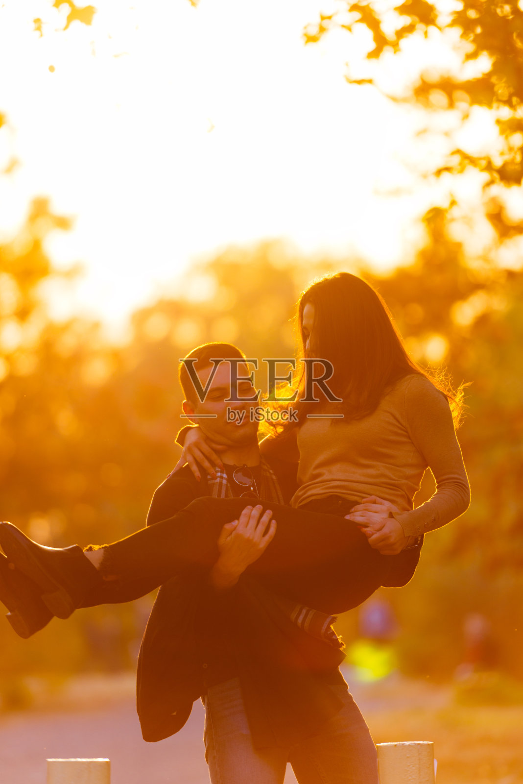 强壮的男朋友在日落时背着他的女朋友。照片摄影图片