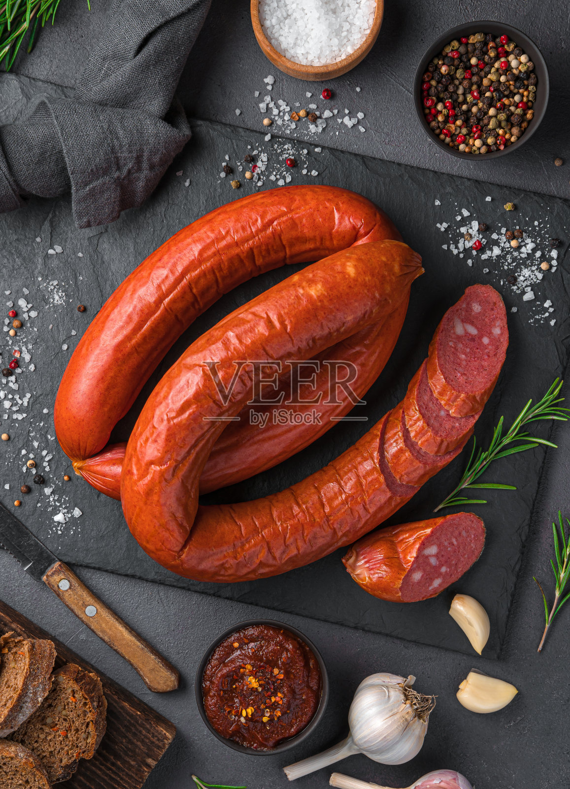 在黑色背景上熏香肠，加入香料、酱汁和大蒜照片摄影图片