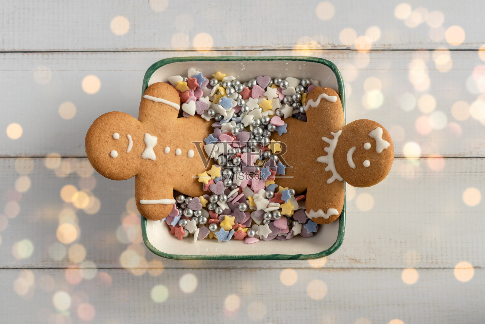 两个姜饼人在一个盛满糖的碗里。照片摄影图片