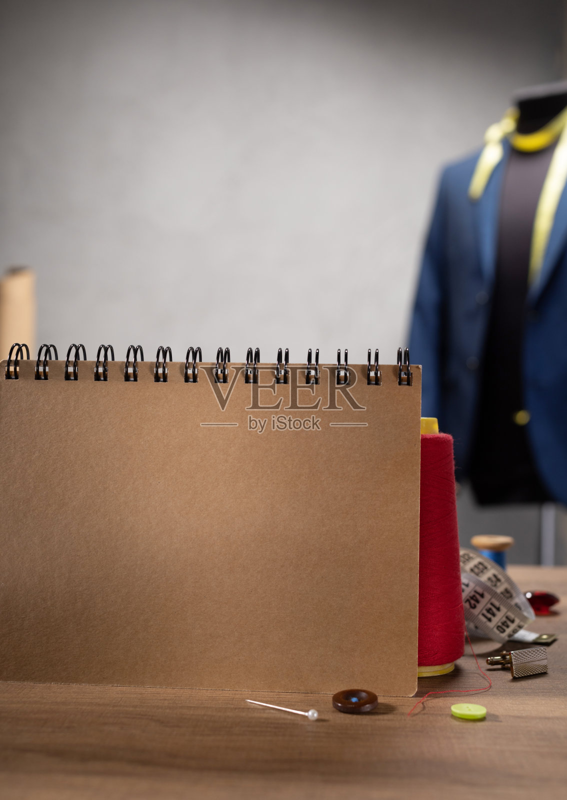 桌上摆放笔记本及缝纫工具。服装工作室工作场所的概念照片摄影图片